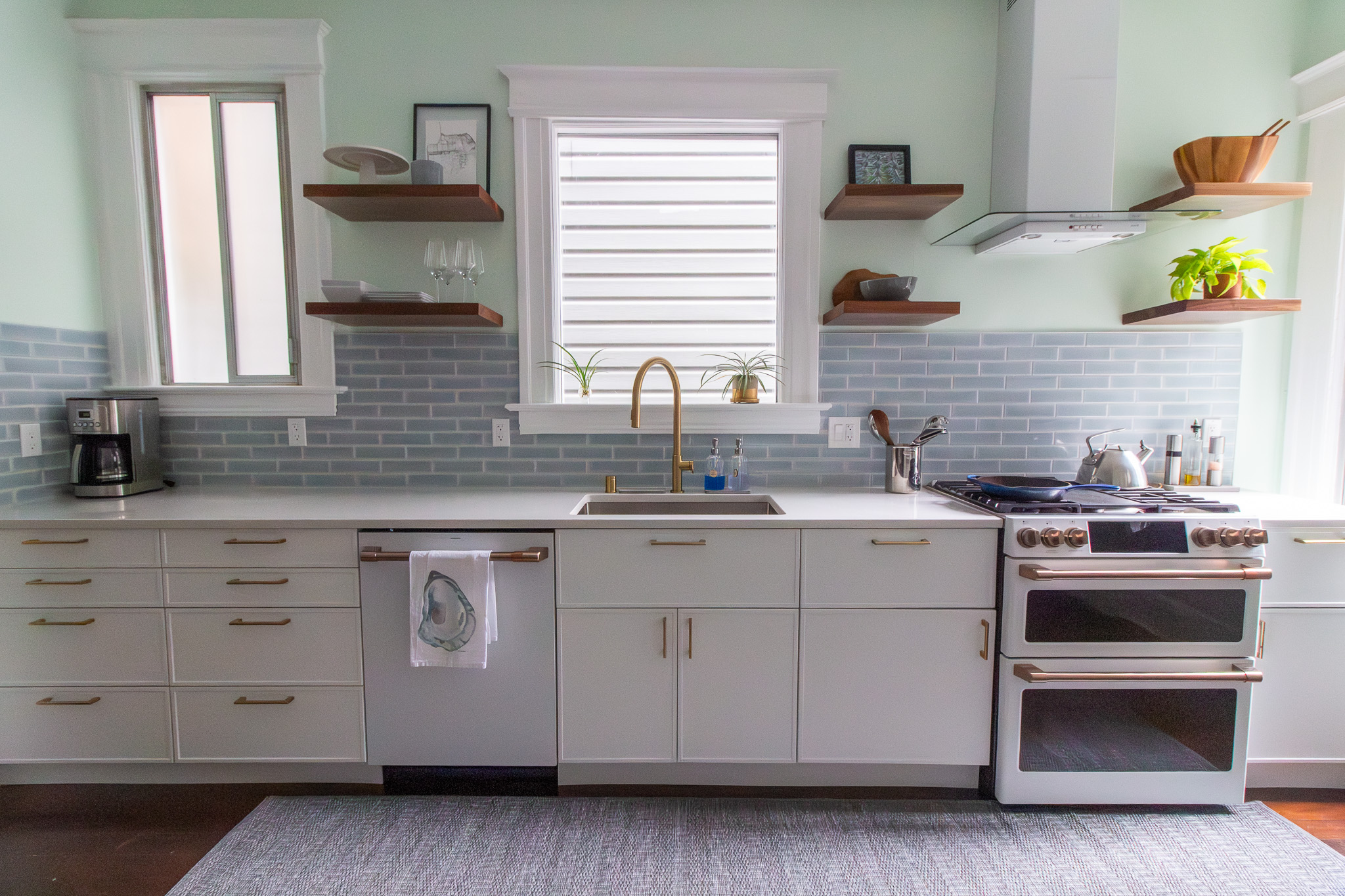 kitchen with white cabinets blue tile and walnut floating shelves