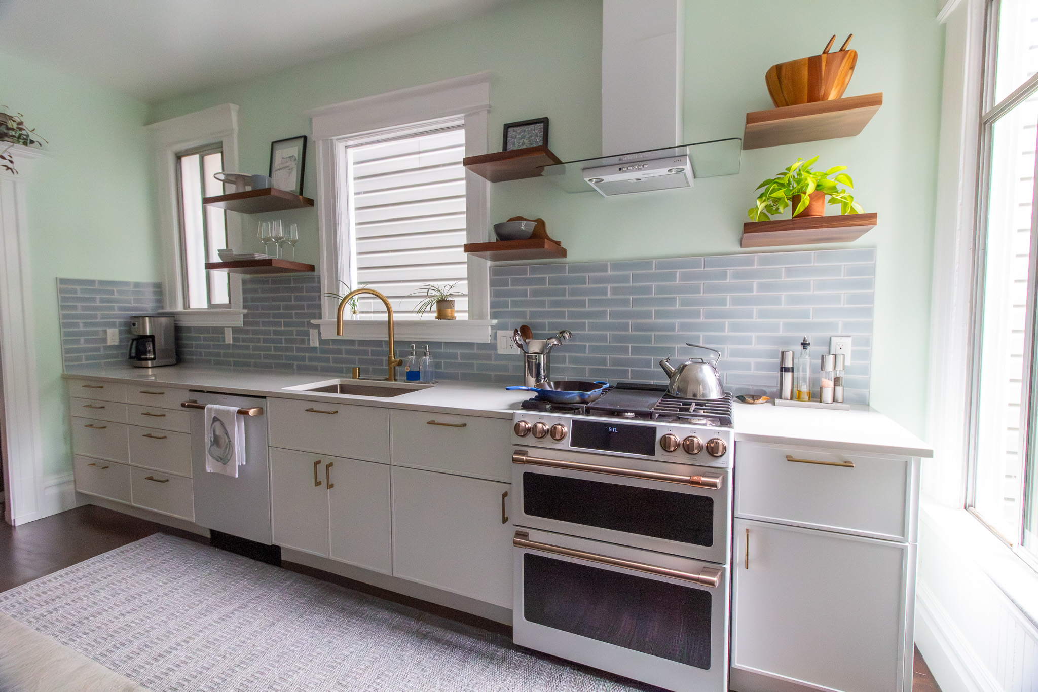 kitchen with white cabinets blue tile and walnut floating shelves