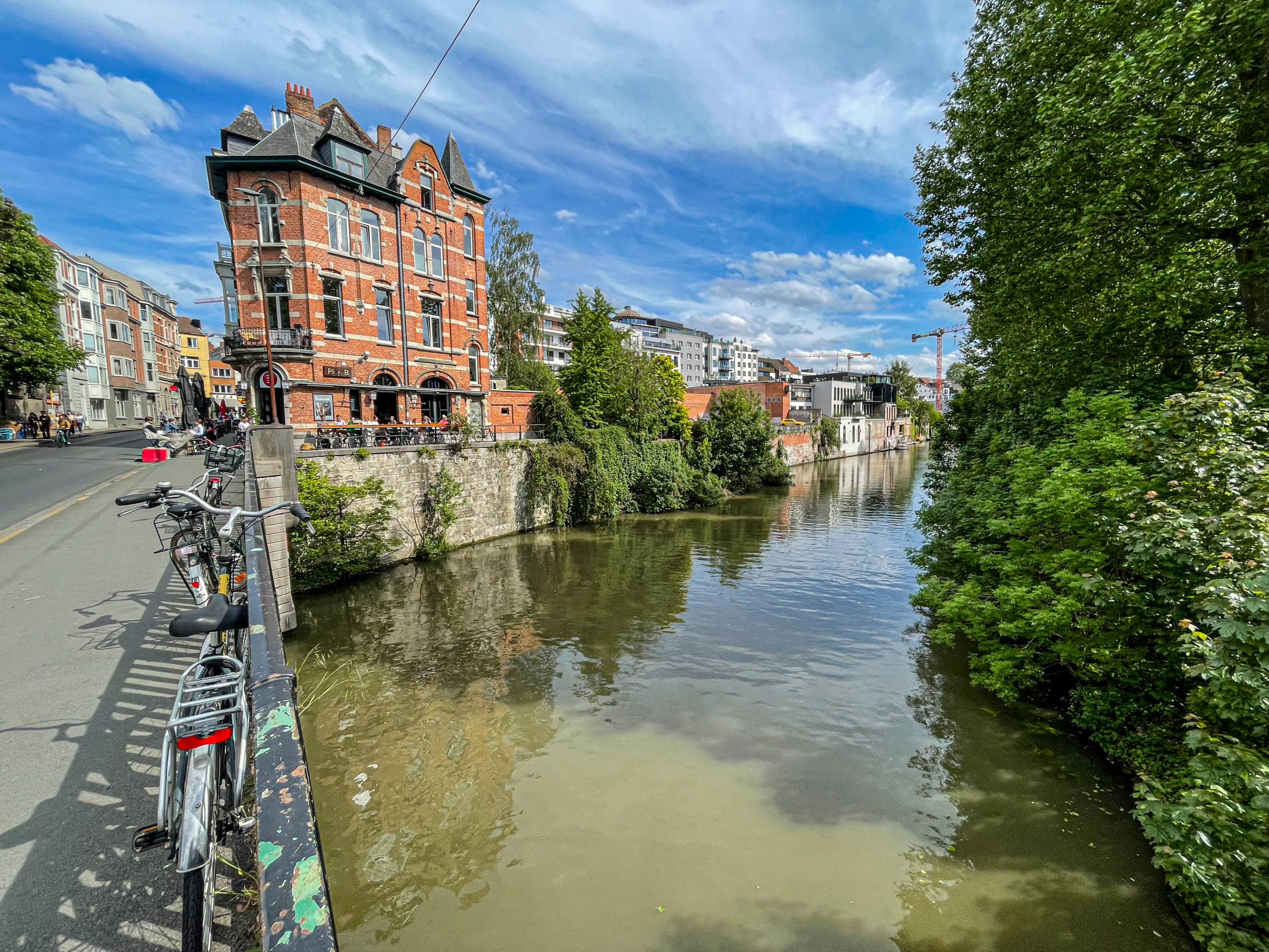 bikes parked along the canal with a red brick building in Ghent Belgium