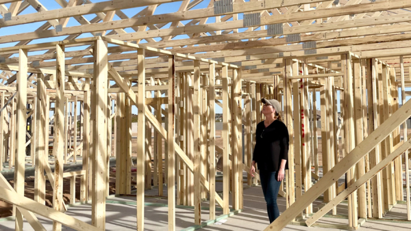 architect walking on a construction site looking at framing of a house