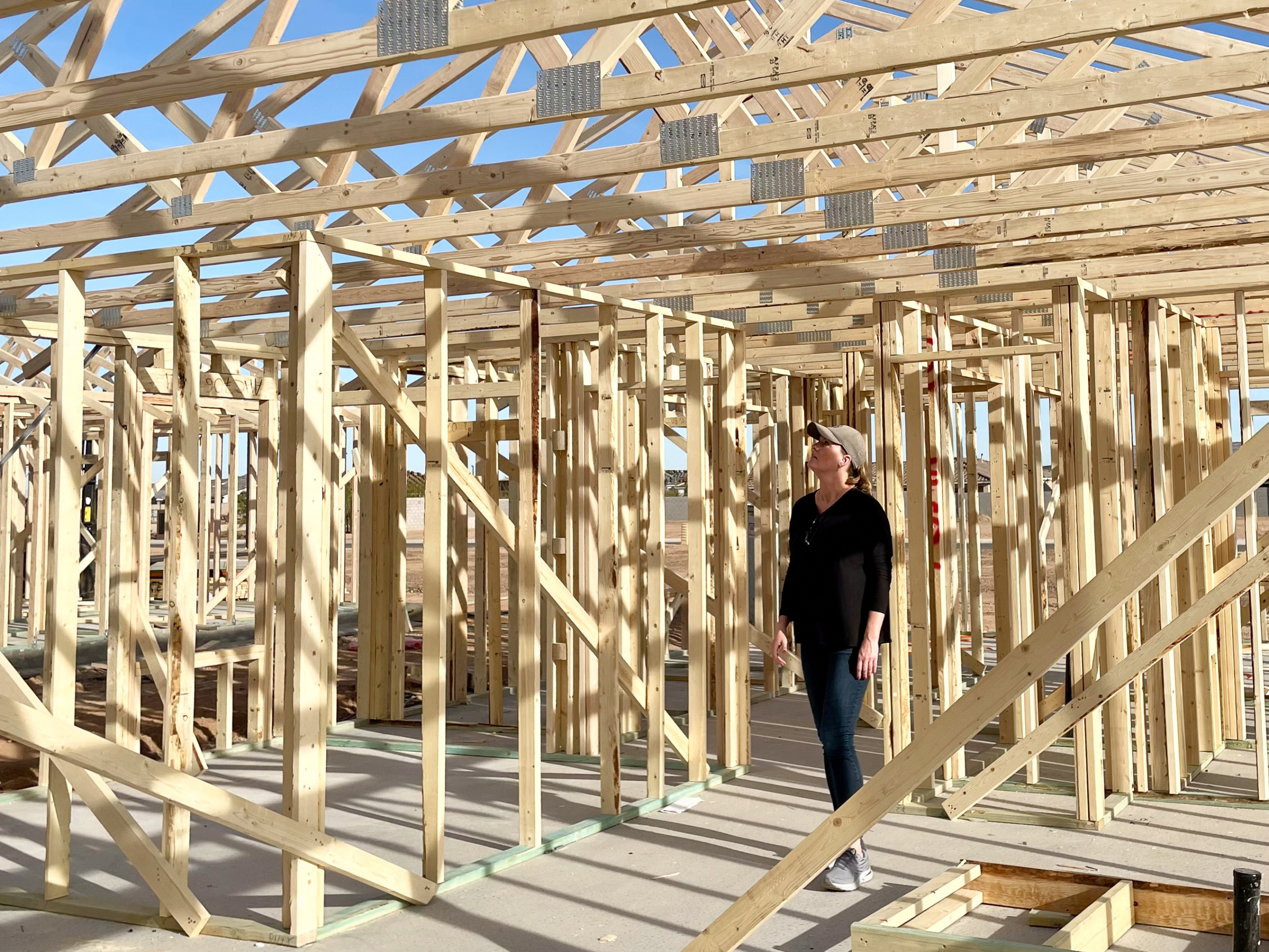 architect walking on a construction site looking at framing of a house