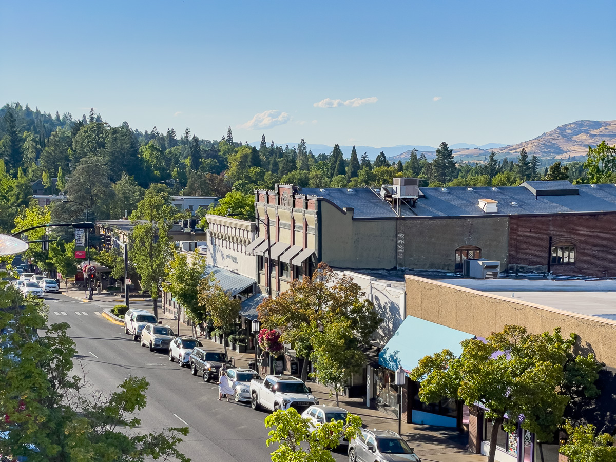 Overlooking Main Street in Ashland Oregon with pine trees in the background and historic brick buildings, charming town in Southern Oregon